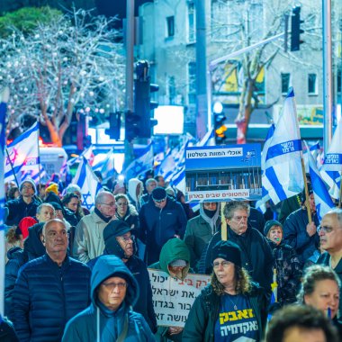 Hayfa, İsrail - 22 Şubat 2025: Çeşitli tabela ve bayraklara sahip bir grup insan, savaşın sona ermesi, rehine anlaşmasının tamamlanması ve yeni seçimler için düzenlenen protesto mitingine katıldı. Hayfa, İsrail