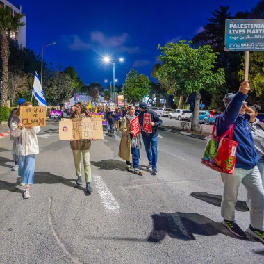 Hayfa, İsrail - 01 Mart 2025: İnsanlar çeşitli işaret ve bayraklarla bir protesto yürüyüşüne katılıyor, savaşın sona ermesi ve rehine anlaşmasının tamamlanması çağrısında bulunuyorlar. Hayfa, İsrail