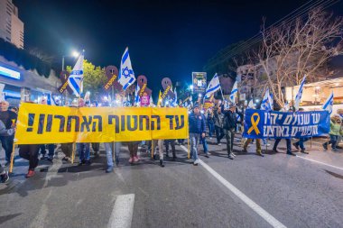 Hayfa, İsrail - 01 Mart 2025: Çeşitli tabelaları ve bayrakları olan insanlar, savaşın sona ermesi, rehine anlaşmasının tamamlanması ve yeni seçimlerin başlatılması için düzenlenen protesto mitingine katıldılar. Hayfa, İsrail