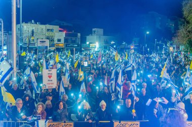 Hayfa, İsrail - 01 Mart 2025: Çeşitli tabela ve bayraklara sahip bir grup insan, savaşın sona ermesi, rehine anlaşmasının tamamlanması ve yeni seçimler için düzenlenen protesto mitingine katıldı. Hayfa, İsrail