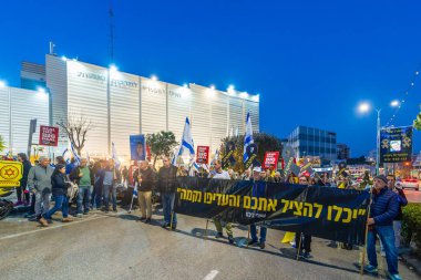 Hayfa, İsrail - 08 Mart 2025: Çeşitli tabelaları ve bayrakları olan insanlar, savaşın sona ermesi, rehine anlaşmasının tamamlanması ve yeni seçimlerin başlatılması için düzenlenen protesto mitingine katıldılar. Hayfa, İsrail