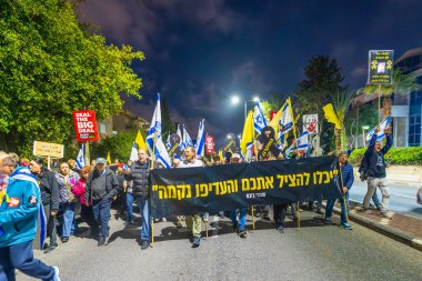 Hayfa, İsrail - 08 Mart 2025: Çeşitli tabelaları ve bayrakları olan insanlar, savaşın sona ermesi, rehine anlaşmasının tamamlanması ve yeni seçimlerin başlatılması için düzenlenen protesto mitingine katıldılar. Hayfa, İsrail