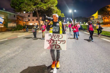 Hayfa, İsrail - 08 Mart 2025: Çeşitli tabelaları ve bayrakları olan insanlar, savaşın sona ermesi, rehine anlaşmasının tamamlanması ve yeni seçimlerin başlatılması için düzenlenen protesto mitingine katıldılar. Hayfa, İsrail