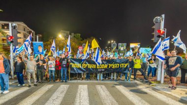 Hayfa, İsrail - 15 Mart 2025: Çeşitli tabelaları ve bayrakları olan insanlar, savaşın sona ermesi, rehine anlaşmasının tamamlanması ve yeni seçimlerin başlatılması için düzenlenen protesto mitingine katıldılar. Hayfa, İsrail