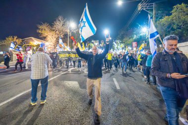 Hayfa, İsrail - 15 Mart 2025: Çeşitli tabelaları ve bayrakları olan insanlar, savaşın sona ermesi, rehine anlaşmasının tamamlanması ve yeni seçimlerin başlatılması için düzenlenen protesto mitingine katıldılar. Hayfa, İsrail