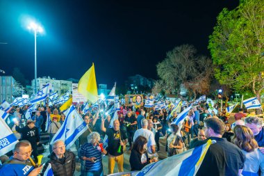 Hayfa, İsrail - 15 Mart 2025: Çeşitli tabela ve bayraklara sahip bir grup insan, savaşın sona ermesi, rehine anlaşmasının tamamlanması ve yeni seçimler için düzenlenen protesto mitingine katıldı. Hayfa, İsrail