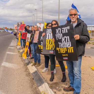 Ein HaMifratz, İsrail - 21 Mart 2025: Rehine posterleri ve diğer tabelaları olan kişiler, otoyol kenarında, rehinelere destek çağrısında bulunarak, savaşı durdurun ve anlaşmayı tamamlayın, Ein HaMifratz, İsrail