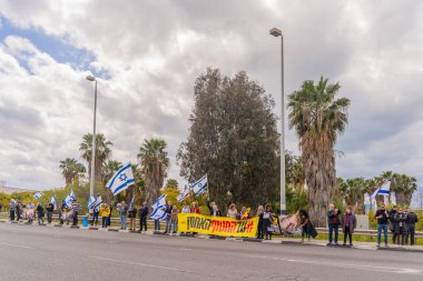 Ein HaMifratz, İsrail - 21 Mart 2025: Rehine posterleri ve diğer tabelaları olan kişiler, otoyol kenarında, rehinelere destek çağrısında bulunarak, savaşı durdurun ve anlaşmayı tamamlayın, Ein HaMifratz, İsrail
