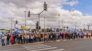 Ein HaMifratz, İsrail - 21 Mart 2025: Rehine posterleri ve diğer tabelaları olan kişiler, otoyol kenarında, rehinelere destek çağrısında bulunarak, savaşı durdurun ve anlaşmayı tamamlayın, Ein HaMifratz, İsrail