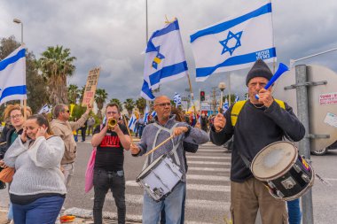 Ein HaMifratz, İsrail - 21 Mart 2025: Rehine posterleri ve diğer tabelaları olan kişiler, otoyol kenarında, rehinelere destek çağrısında bulunarak, savaşı durdurun ve anlaşmayı tamamlayın, Ein HaMifratz, İsrail