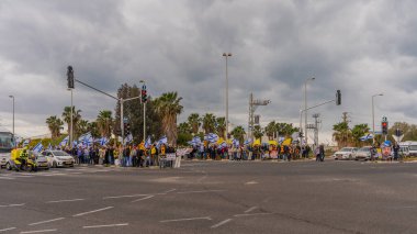 Ein HaMifratz, İsrail - 21 Mart 2025: Rehine posterleri ve diğer tabelaları olan kişiler, otoyol kenarında, rehinelere destek çağrısında bulunarak, savaşı durdurun ve anlaşmayı tamamlayın, Ein HaMifratz, İsrail