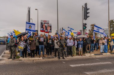 Ein HaMifratz, İsrail - 21 Mart 2025: Rehine posterleri ve diğer tabelaları olan kişiler, otoyol kenarında, rehinelere destek çağrısında bulunarak, savaşı durdurun ve anlaşmayı tamamlayın, Ein HaMifratz, İsrail