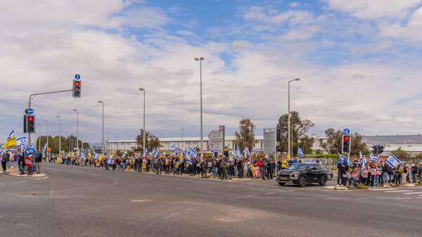 Ein HaMifratz, Israel - March 21, 2025: People with hostage posters and other signs, near a highway, calling for support of the hostages, stop the war and completion of the deal, Ein HaMifratz, Israel