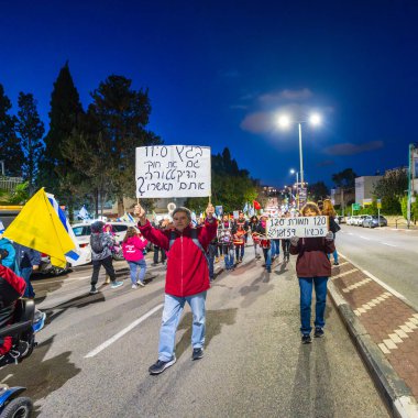 Hayfa, İsrail - 22 Mart 2025: İnsanlar çeşitli işaret ve bayraklarla bir protesto yürüyüşüne katılıyor, savaşın sona ermesi ve rehine anlaşmasının tamamlanması çağrısında bulunuyorlar. Hayfa, İsrail