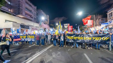 Hayfa, İsrail - 22 Mart 2025: İnsanlar çeşitli işaret ve bayraklarla bir protesto yürüyüşüne katılıyor, savaşın sona ermesi ve rehine anlaşmasının tamamlanması çağrısında bulunuyorlar. Hayfa, İsrail