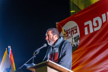 Hayfa, İsrail - 22 Mart 2025: İnsanlar çeşitli işaret ve bayraklarla bir protesto yürüyüşüne katılıyor, savaşın sona ermesi ve rehine anlaşmasının tamamlanması çağrısında bulunuyorlar. Hayfa, İsrail