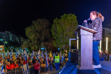 Hayfa, İsrail - 22 Mart 2025: İnsanlar çeşitli işaret ve bayraklarla bir protesto yürüyüşüne katılıyor, savaşın sona ermesi ve rehine anlaşmasının tamamlanması çağrısında bulunuyorlar. Hayfa, İsrail