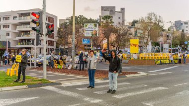 Hayfa, İsrail - 23 Mart 2025: Tabela ve bayraklı insanların günlük protesto gösterileri, rehineleri desteklemek ve anlaşmanın Hayfa, İsrail 'de tamamlanması yönünde çağrıda bulunmaları