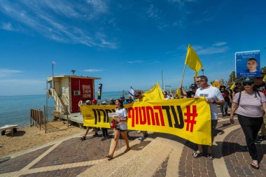 Hayfa, İsrail - 28 Mart 2025: İnsanlar, Hamas aileleri tarafından kaçırılan rehinelere destek olmak amacıyla sahil boyunca pankartlar, pankartlar ve bayraklarla yürüyüş yaparak anlaşma çağrısında bulundular. Hayfa, İsrail