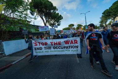 Hayfa, İsrail - 29 Mart 2025: İnsanlar çeşitli işaret ve bayraklarla bir protesto yürüyüşüne katılıyor, savaşın sona ermesi ve rehine anlaşmasının tamamlanması çağrısında bulunuyorlar. Hayfa, İsrail