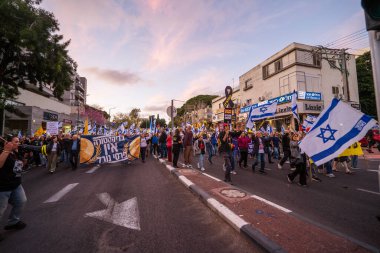 Hayfa, İsrail - 29 Mart 2025: Çeşitli tabelaları ve bayrakları olan insanlar, savaşın sona ermesi, rehine anlaşmasının tamamlanması ve yeni seçimlerin başlatılması için düzenlenen protesto mitingine katıldılar. Hayfa, İsrail
