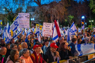 Hayfa, İsrail - 29 Mart 2025: Çeşitli tabela ve bayraklara sahip bir grup insan, savaşın sona ermesi, rehine anlaşmasının tamamlanması ve yeni seçimler için düzenlenen protesto mitingine katıldı. Hayfa, İsrail