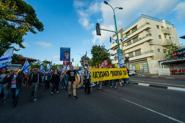 Hayfa, İsrail - 29 Mart 2025: Çeşitli tabelaları ve bayrakları olan insanlar, savaşın sona ermesi, rehine anlaşmasının tamamlanması ve yeni seçimlerin başlatılması için düzenlenen protesto mitingine katıldılar. Hayfa, İsrail