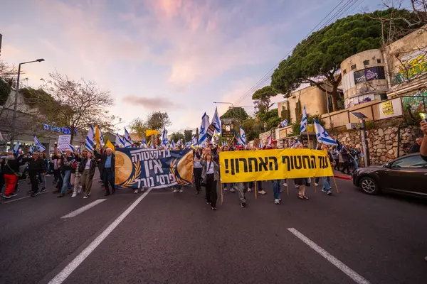 Hayfa, İsrail - 29 Mart 2025: Çeşitli tabelaları ve bayrakları olan insanlar, savaşın sona ermesi, rehine anlaşmasının tamamlanması ve yeni seçimlerin başlatılması için düzenlenen protesto mitingine katıldılar. Hayfa, İsrail