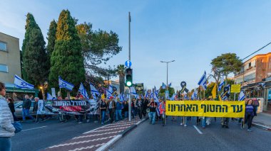 Hayfa, İsrail - Nisan 05, 2025: Çeşitli tabela ve bayraklara sahip insanlar savaşın sona ermesi, rehine anlaşmasının tamamlanması ve yeni seçimler için düzenlenen protesto mitingine katıldılar. Hayfa, İsrail