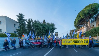 Hayfa, İsrail - Nisan 05, 2025: Çeşitli tabela ve bayraklara sahip insanlar savaşın sona ermesi, rehine anlaşmasının tamamlanması ve yeni seçimler için düzenlenen protesto mitingine katıldılar. Hayfa, İsrail