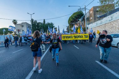 Hayfa, İsrail - Nisan 05, 2025: Çeşitli tabela ve bayraklara sahip insanlar savaşın sona ermesi, rehine anlaşmasının tamamlanması ve yeni seçimler için düzenlenen protesto mitingine katıldılar. Hayfa, İsrail