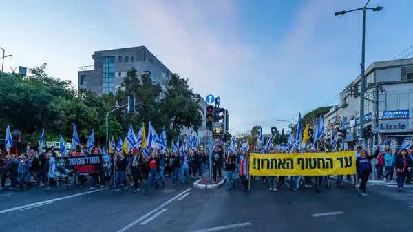 Hayfa, İsrail - Nisan 05, 2025: Çeşitli tabela ve bayraklara sahip insanlar savaşın sona ermesi, rehine anlaşmasının tamamlanması ve yeni seçimler için düzenlenen protesto mitingine katıldılar. Hayfa, İsrail