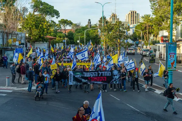 Hayfa, İsrail - Nisan 05, 2025: Çeşitli tabela ve bayraklara sahip insanlar savaşın sona ermesi, rehine anlaşmasının tamamlanması ve yeni seçimler için düzenlenen protesto mitingine katıldılar. Hayfa, İsrail