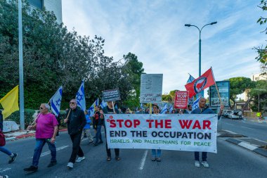 Hayfa, İsrail - Nisan 05, 2025: İnsanlar çeşitli işaret ve bayraklarla bir protesto yürüyüşüne katılıyor, savaşı sona erdirme ve rehine anlaşmasının tamamlanması çağrısında bulunuyorlar. Hayfa, İsrail