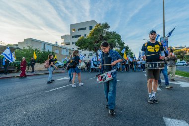 Hayfa, İsrail - Nisan 05, 2025: Çeşitli tabela ve bayraklara sahip insanlar savaşın sona ermesi, rehine anlaşmasının tamamlanması ve yeni seçimler için düzenlenen protesto mitingine katıldılar. Hayfa, İsrail