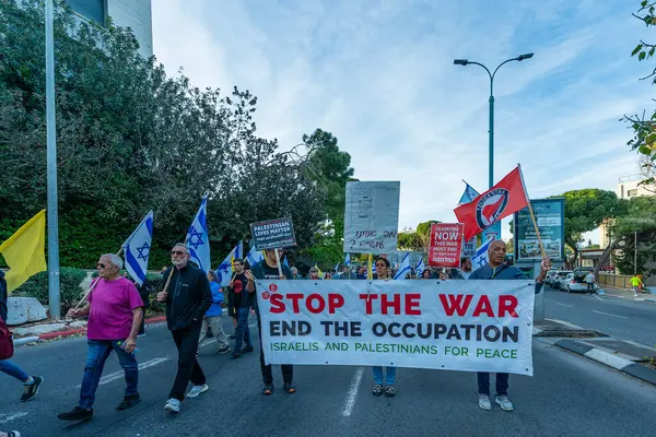 Hayfa, İsrail - Nisan 05, 2025: İnsanlar çeşitli işaret ve bayraklarla bir protesto yürüyüşüne katılıyor, savaşı sona erdirme ve rehine anlaşmasının tamamlanması çağrısında bulunuyorlar. Hayfa, İsrail