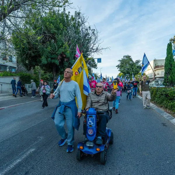 Hayfa, İsrail - Nisan 05, 2025: Çeşitli tabela ve bayraklara sahip insanlar savaşın sona ermesi, rehine anlaşmasının tamamlanması ve yeni seçimler için düzenlenen protesto mitingine katıldılar. Hayfa, İsrail