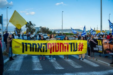 Ein HaMifratz, İsrail - 10 Nisan 2025: Rehine posterleri ve diğer tabelaları olan insanlar, otoyolun yakınında, rehinelere destek çağrısında bulunuyorlar ve anlaşmanın tamamlanmasını istiyorlar, Ein HaMifratz, İsrail