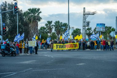 Ein HaMifratz, İsrail - 10 Nisan 2025: Rehine posterleri ve diğer tabelaları olan insanlar, otoyolun yakınında, rehinelere destek çağrısında bulunuyorlar ve anlaşmanın tamamlanmasını istiyorlar, Ein HaMifratz, İsrail