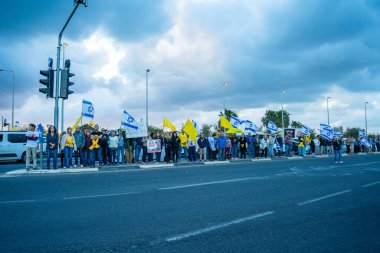 Ein HaMifratz, İsrail - 10 Nisan 2025: Rehine posterleri ve diğer tabelaları olan insanlar, otoyolun yakınında, rehinelere destek çağrısında bulunuyorlar ve anlaşmanın tamamlanmasını istiyorlar, Ein HaMifratz, İsrail