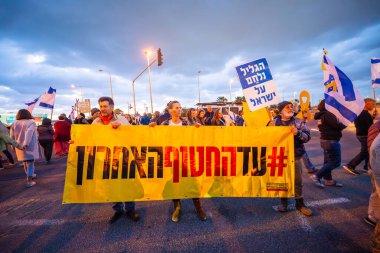 Ein HaMifratz, İsrail - 10 Nisan 2025: Rehine posterleri ve diğer tabelaları olan insanlar, otoyolun yakınında, rehinelere destek çağrısında bulunuyorlar ve anlaşmanın tamamlanmasını istiyorlar, Ein HaMifratz, İsrail