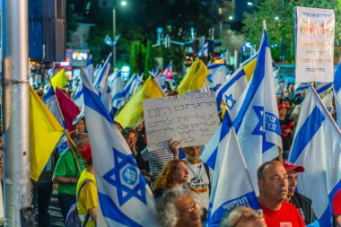 Hayfa, İsrail - 19 Nisan 2025: Çeşitli tabela ve bayraklara sahip bir grup insan, savaşın sona ermesi, rehine anlaşmasının tamamlanması ve yeni seçimler için düzenlenen protesto mitingine katıldı. Hayfa, İsrail