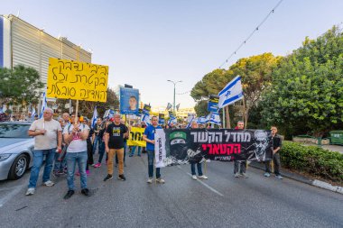 Hayfa, İsrail - 19 Nisan 2025: Çeşitli tabelaları ve bayrakları olan insanlar, savaşın sona ermesi, rehine anlaşmasının tamamlanması ve yeni seçimlerin başlatılması için düzenlenen protesto mitingine katıldılar. Hayfa, İsrail