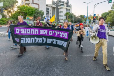 Hayfa, İsrail - 19 Nisan 2025: İnsanlar savaşın sona ermesi, rehine anlaşmasının tamamlanması ve yeni seçimler çağrısında bulunan bir protesto yürüyüşüne katılıyor. Hayfa, İsrail