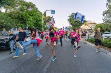 Hayfa, İsrail - 19 Nisan 2025: İnsanlar savaşın sona ermesi, rehine anlaşmasının tamamlanması ve yeni seçimler çağrısında bulunan bir protesto yürüyüşüne (Pembe Cephe Grubu) katılıyor. Hayfa, İsrail