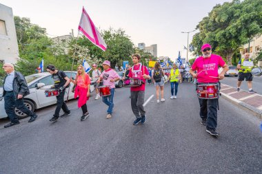 Hayfa, İsrail - 19 Nisan 2025: İnsanlar savaşın sona ermesi, rehine anlaşmasının tamamlanması ve yeni seçimler çağrısında bulunan bir protesto yürüyüşüne (Pembe Cephe Grubu) katılıyor. Hayfa, İsrail