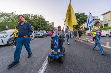 Hayfa, İsrail - 19 Nisan 2025: Çeşitli tabelaları ve bayrakları olan insanlar, savaşın sona ermesi, rehine anlaşmasının tamamlanması ve yeni seçimlerin başlatılması için düzenlenen protesto mitingine katıldılar. Hayfa, İsrail