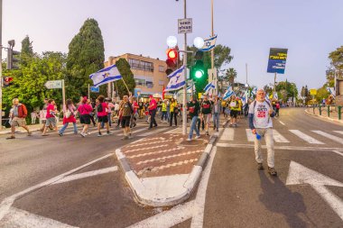 Hayfa, İsrail - 19 Nisan 2025: Çeşitli tabelaları ve bayrakları olan insanlar, savaşın sona ermesi, rehine anlaşmasının tamamlanması ve yeni seçimlerin başlatılması için düzenlenen protesto mitingine katıldılar. Hayfa, İsrail