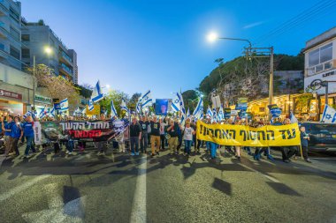 Hayfa, İsrail - 19 Nisan 2025: Çeşitli tabelaları ve bayrakları olan insanlar, savaşın sona ermesi, rehine anlaşmasının tamamlanması ve yeni seçimlerin başlatılması için düzenlenen protesto mitingine katıldılar. Hayfa, İsrail