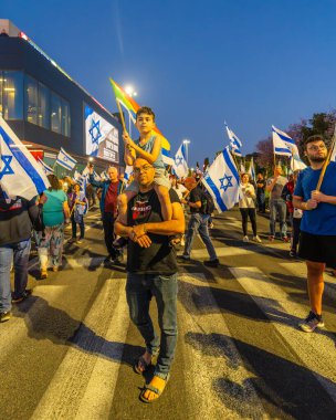 Hayfa, İsrail - 19 Nisan 2025: Çeşitli tabela ve bayraklara sahip bir grup insan, savaşın sona ermesi, rehine anlaşmasının tamamlanması ve yeni seçimler için düzenlenen protesto mitingine katıldı. Hayfa, İsrail